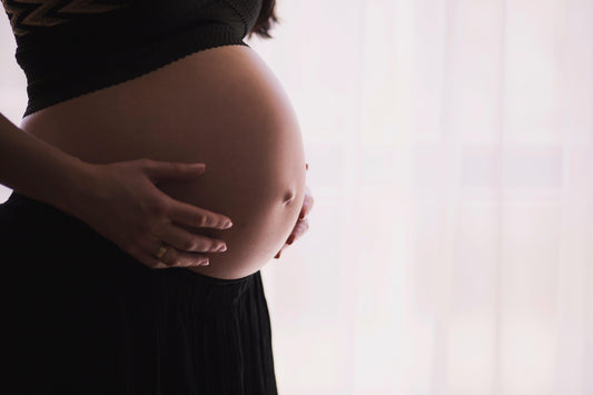 Pregnant woman cradling her baby bump — EMF radiation risks during pregnancy and miscarriage