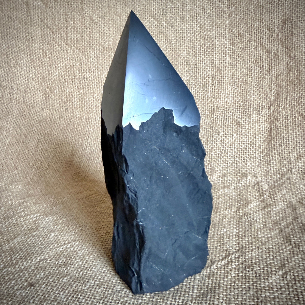 Large Raw Shungite Point standing upright on burlap covered table