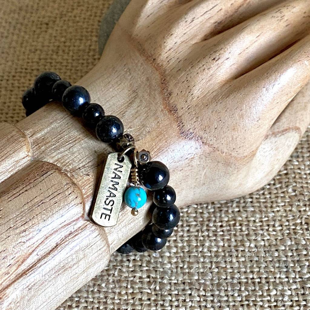 Shungite Namaste Bracelet with Turquoise Bead Dangle on wooden wrist