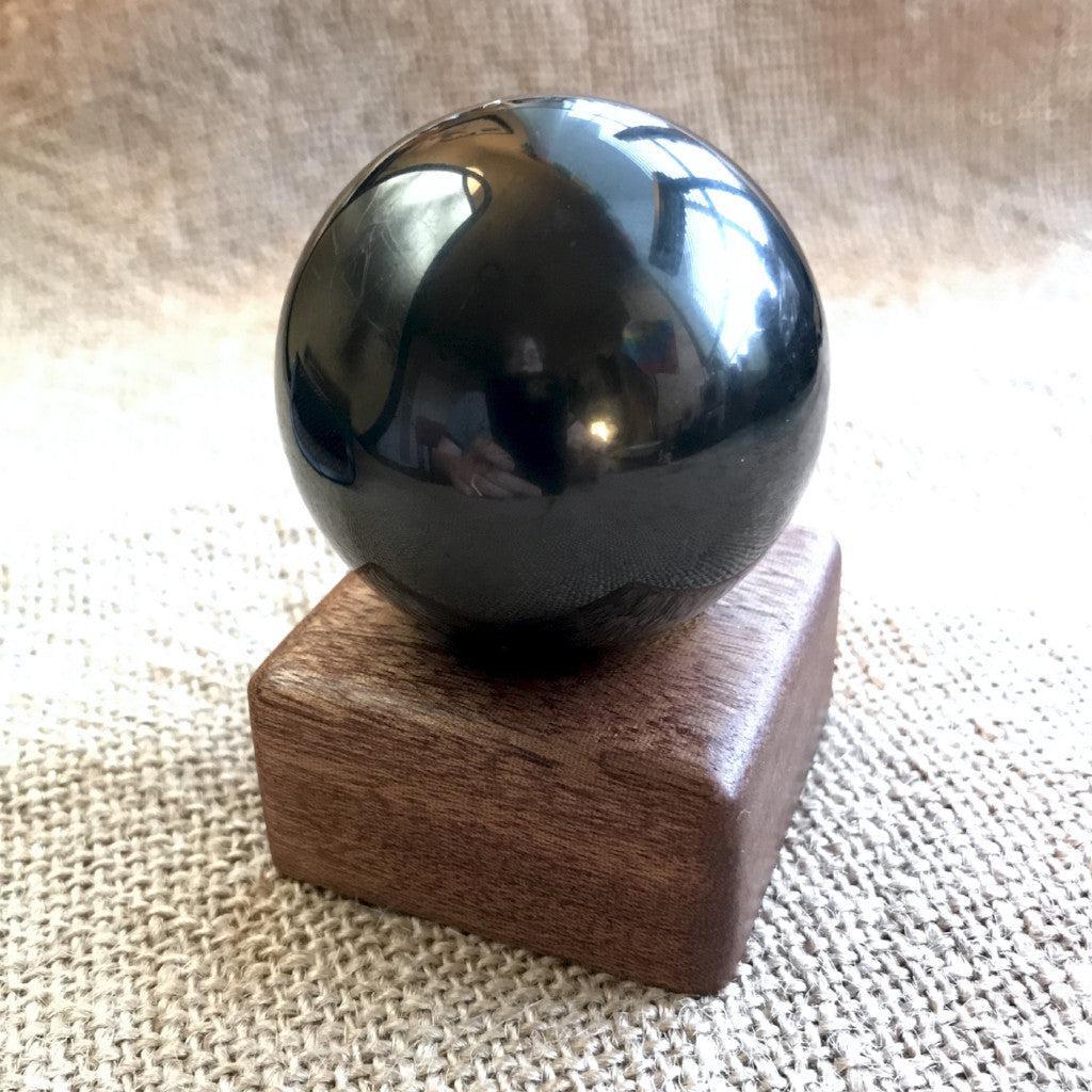 Polished 2-inch shungite sphere on a custom wooden stand