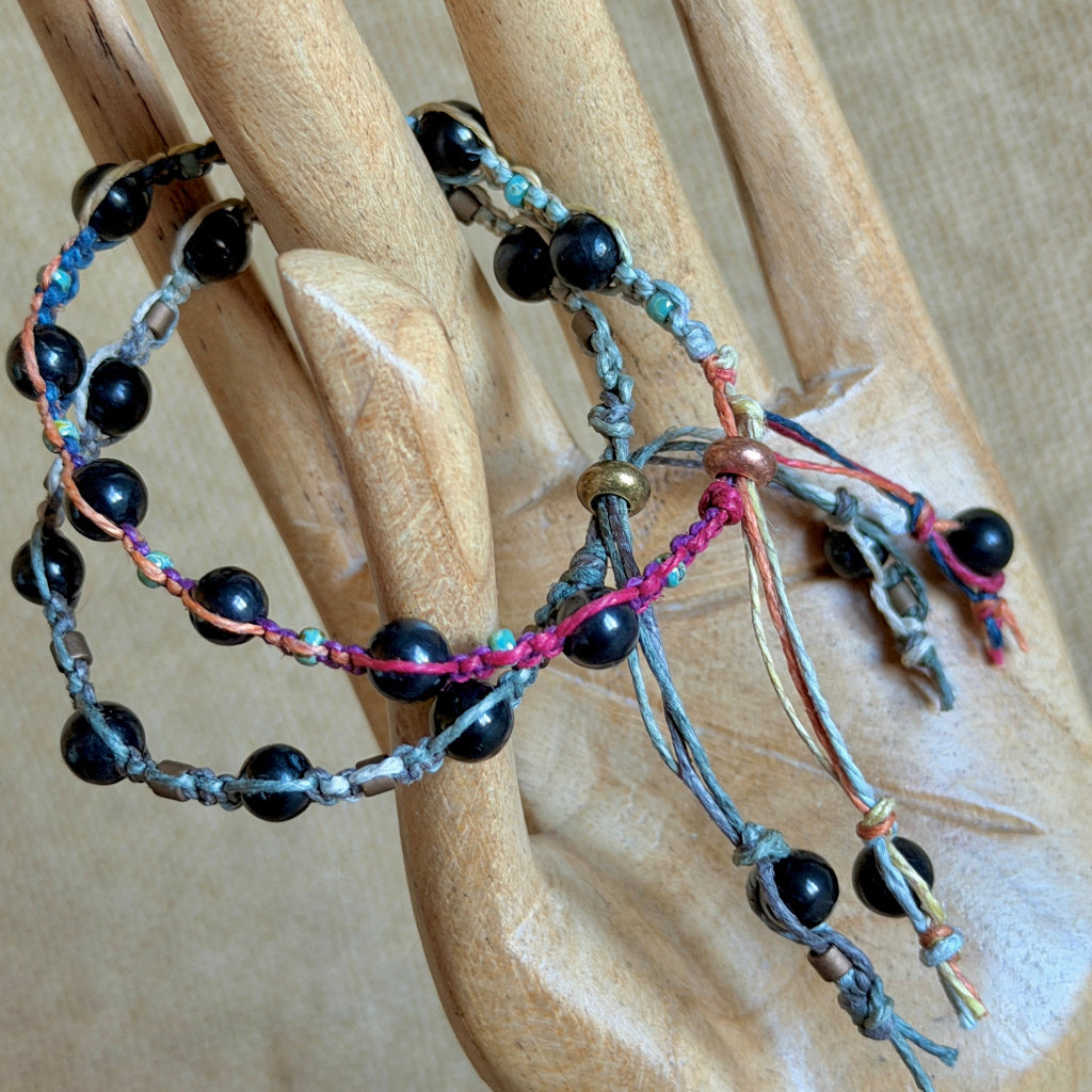 Two Shungite Macrame Bracelets with Variegated Hemp on wooden hand