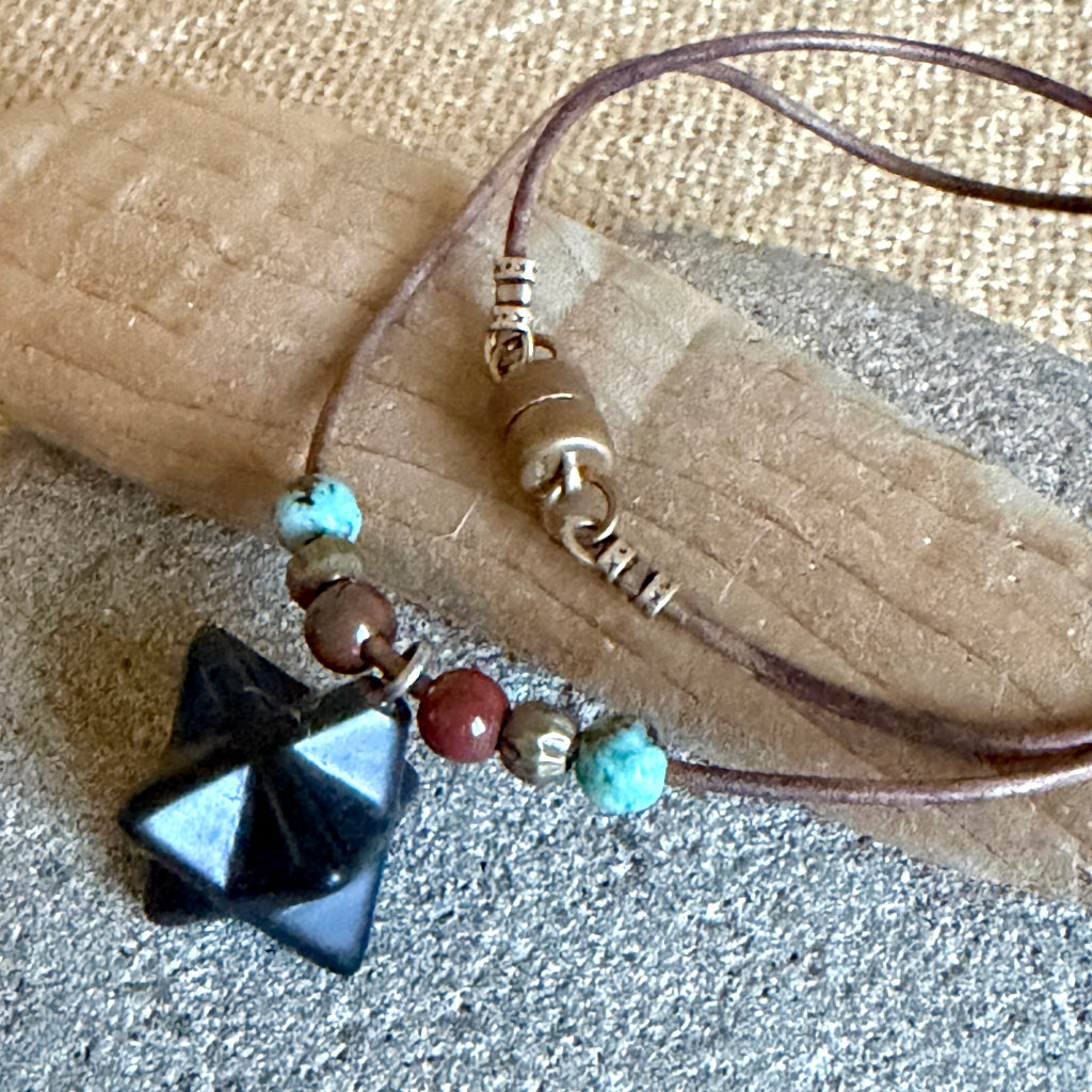 Shungite Merkaba Necklace on driftwood and rock
