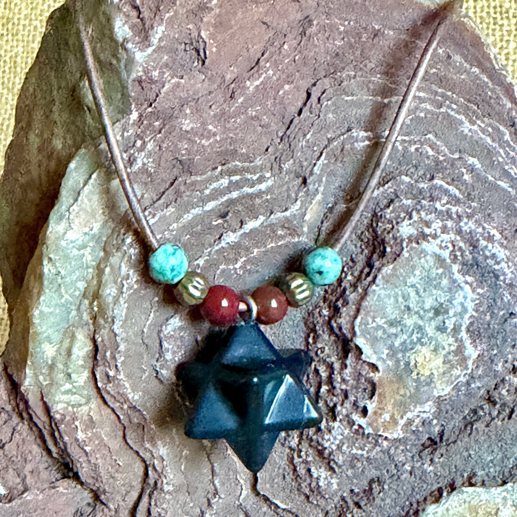 Shungite Merkaba Necklace draped on rock