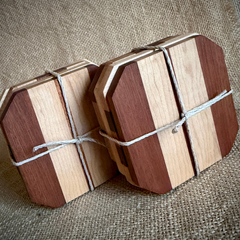 Set of 8 octagonal wooden coasters with alternating light and dark wood stripes, wrapped in white twine, displayed on a burlap background.